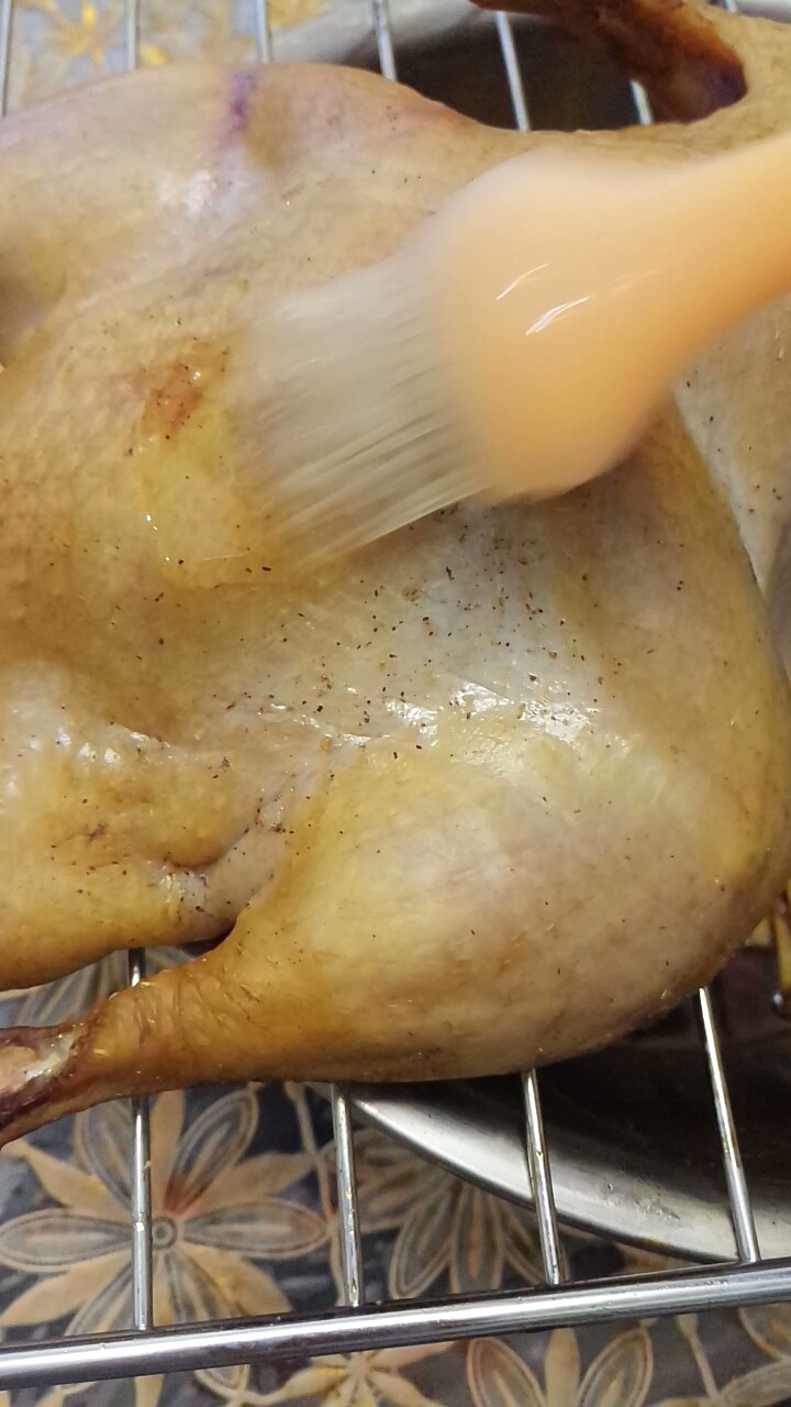 家庭自制烤鸭,将鸭子取出来，再刷一层蜜水。翻个面儿再次放入烤箱中，继续烤半小时