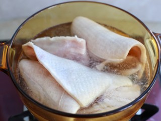 猪皮冻,将猪肉皮用温水洗净，残留的猪毛可以用小镊子拔掉，放入开水锅中加料酒开盖煮约十分钟