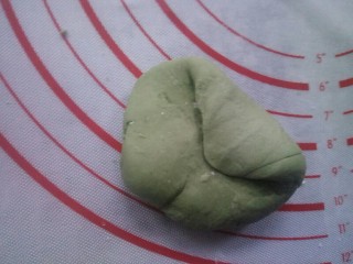 花样馒头——青蛙篇,硅胶垫上撒些许干面粉，防止面团粘连。取一个绿色面团再次揉，进行排气，因为在放置的时间内，面团仍在发酵。将面团边分别往里按……