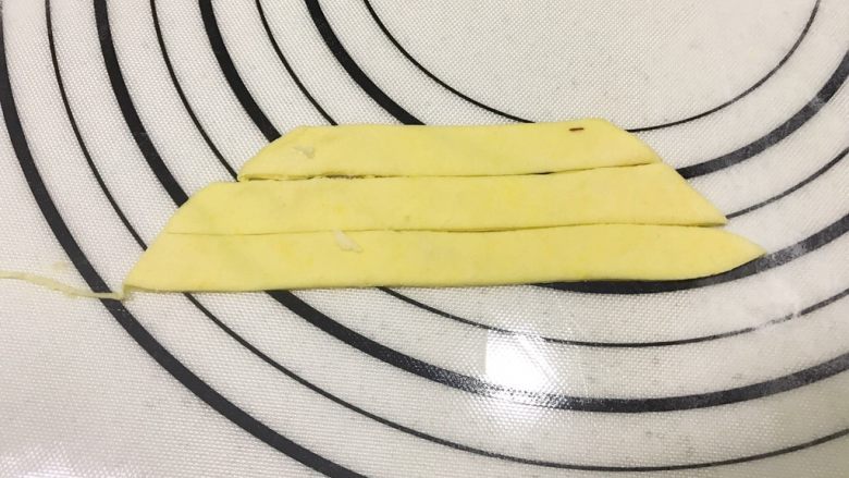 旺财柴犬枣泥包,将刚刚切下来的南瓜面团揉匀后擀成薄片，再均匀的割下宽窄相同的长条