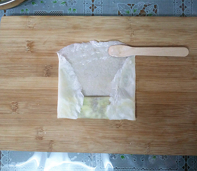 做春卷 黄金万两~韭黄猪肉春卷,按自己喜欢的方式如图折叠、并在饼皮的上沿抹点浆糊方便更好粘连