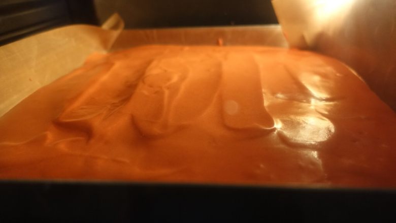 红丝绒波点蛋糕卷,取出烤好的波点，倒入红丝绒蛋糕糊，用管道抹平震泡。放入烤箱继续烤制18-20分钟。
