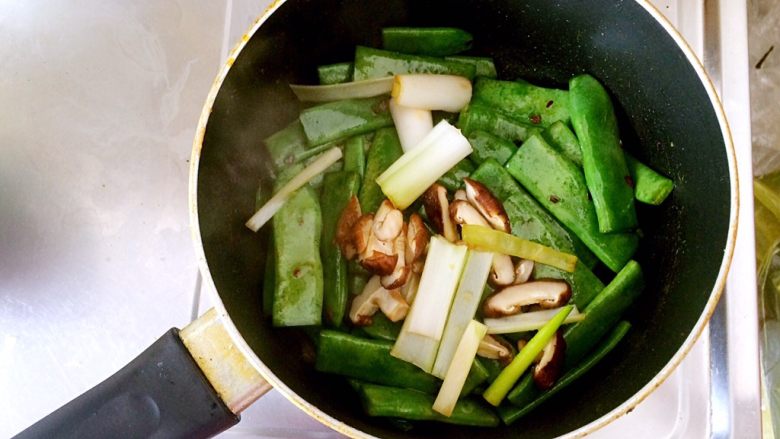 扁豆焖意面,翻炒至颜色呈翠绿色时，加入香菇和葱段。