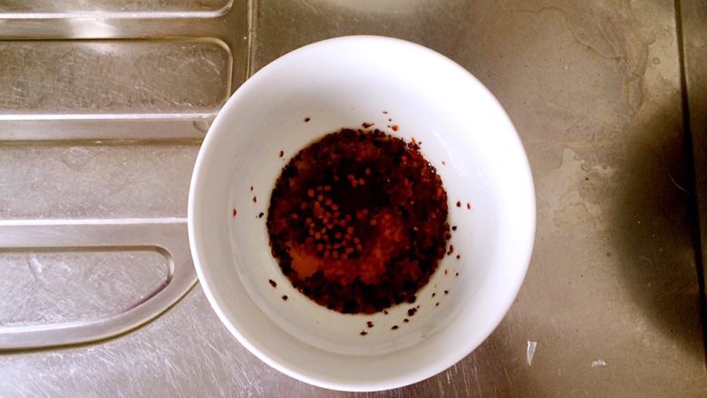 扁豆焖意面,将炒好的有糖色的油，倒三分之一至装有干辣椒碎的小碗内。