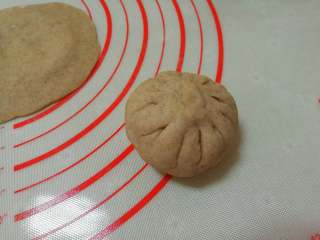黑麦南瓜豆沙包,用手捏成包子状，捏紧收口揉圆，收口朝下放在揉面垫上。