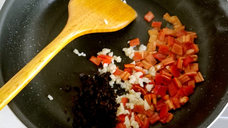 豆豉炒肉丁,锅中放油烧热，放入红椒，大蒜和豆豉。