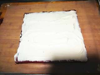 【情人节】红丝绒蛋糕卷,晾凉后台面铺一层油纸，正卷反卷都可以，我是有毛巾面的一面朝下。蛋糕尾部切一斜边，淡奶油加糖打发至8分发铺到蛋糕上