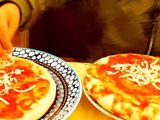DIY亲子披萨,再分别均匀地铺撒适量马苏里拉奶酪。
