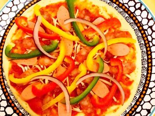 DIY亲子披萨,在9寸披萨上摆放适量三色辣椒丝和洋葱丝。