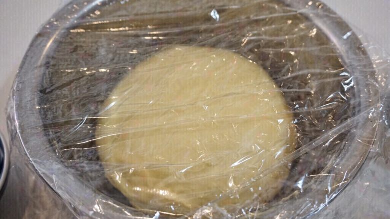 椰浆餐包,盆底撒少量面粉，把面团团圆放进去，盖保鲜膜等待发酵。