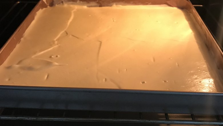 爱心草莓蛋糕卷,放入预热好150度烤箱中，烤20分钟。出炉后从高处摔一下，垫张油纸倒扣在烤网上，撕掉油布，再翻转过来盖上油纸晾凉。