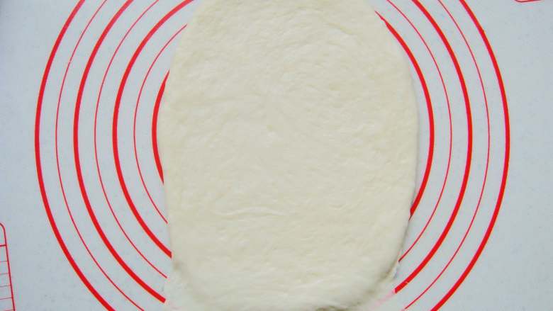 葡萄干软欧包,取一个面团擀成长条薄面片，末端压薄（利于封口）