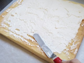 原味蛋糕卷
（正卷）,均匀的铺上淡奶油，沿着切边，一端奶油厚一点一端薄点。