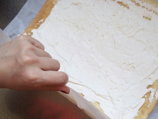 原味蛋糕卷
（正卷）,提起厚断奶油一侧的油纸往里卷，手法要轻柔迅速，犹犹豫豫会卷裂