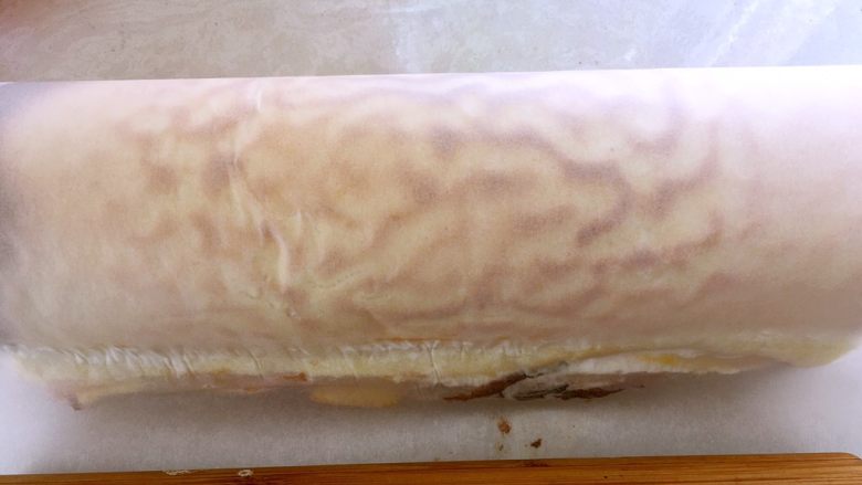 虎皮蛋糕卷,利用擀面杖将蛋糕卷卷起，之后在用擀面杖压一下，抽紧油纸，让蛋糕卷的紧实些，之后放冰箱冷藏半个小时