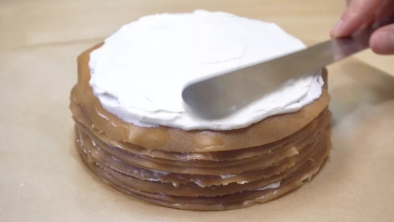 摩卡咖啡千层蛋糕,将打发的淡奶油，逐层涂抹在薄饼上，四周留一个边儿不涂奶油。