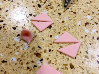 卡通馒头,把压完猪鼻子剩的粉色面皮 切成一个四方型、再等分成四个小方块、一个小方块再切成两个三角形用来做猪耳朵
三角朝里对折 可以粘一点点牛奶帮助粘合