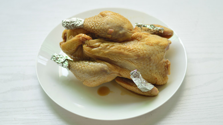 柠香烤全鸡,隔天将腌好的鸡取出，将容易烤糊的鸡尖和鸡腿末裹上锡纸