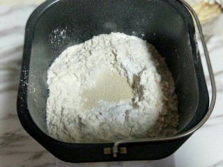 南瓜豆沙花纹水立方吐司面包,再加入高筋面粉，最后再面粉的顶端挖个小洞，(不要挖到液体) 把酵母粉倒入挖好的洞洞里。再用旁边的面粉将酵母粉盖上。