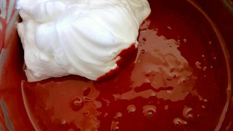 红曲蛋糕卷,蛋黄糊中加入3分之一的蛋白。刮刀切拌或者翻拌，用手抽也可以。切记不要画圈搅拌，画圈会消泡，消泡的蛋糕糊会导致蛋糕发不起来。所以这一步很关键哟。