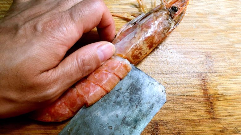 蒜蓉芝士焗阿根廷红虾,用菜刀把虾肉切开，不要切断（这是我老公的手，有点黑，将就看哈，哈哈题外话）