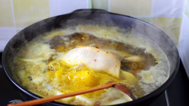 盐焗鸡,用勺子轻轻翻动一下三黄鸡、以免鸡皮粘到锅里、影响颜值