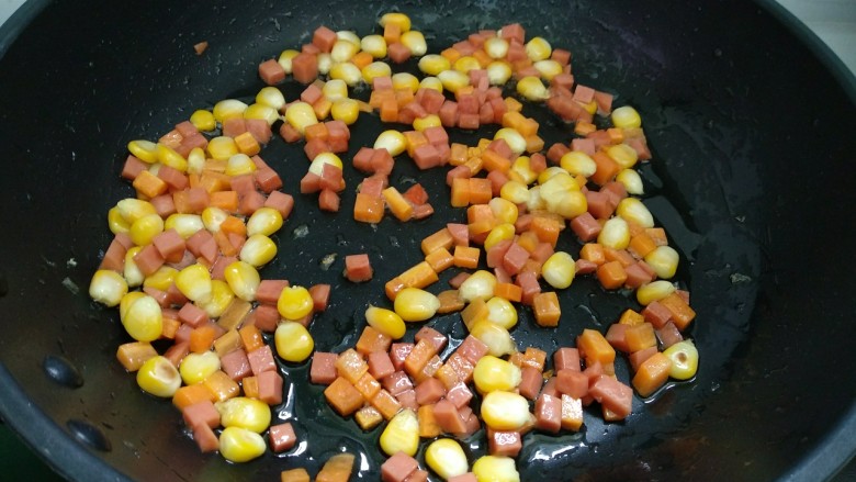 翠竹报春咖喱饭,倒入胡萝卜，玉米粒和火腿肠翻炒至快熟。