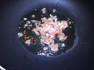 酸豆角肉丁米线,锅中放油，油热之后放入干辣椒爆香，再放入肉丁翻炒