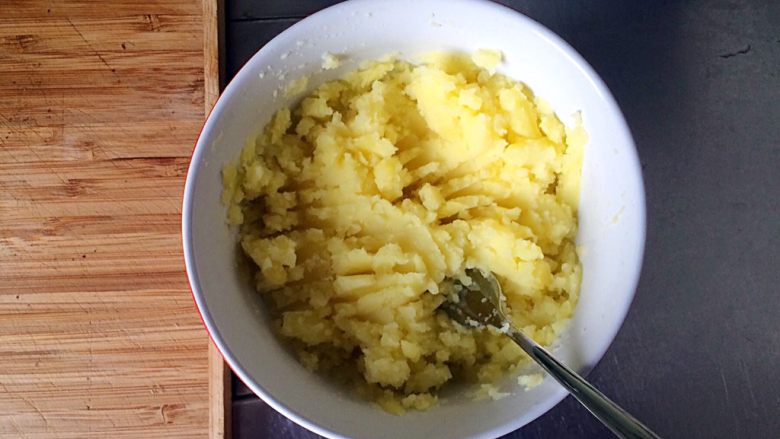 土豆牛肉丸子烩饭,用勺子或叉子将蒸熟的土豆捣碎成泥。
