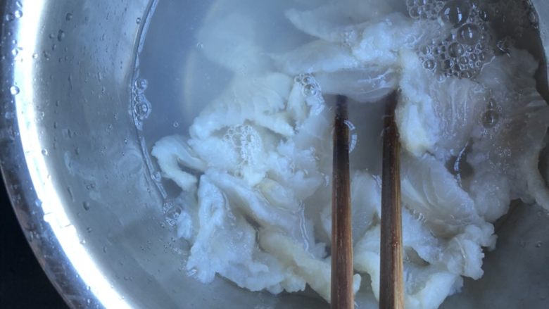 水煮龙利鱼,煮菜的过程中，在腌鱼片的碗中倒入沸水，用筷子剥散鱼片，沥去混浊的水。这一步可以避免在煮鱼片时出现过多浮末。