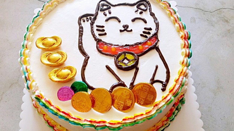 招财猫蛋糕,挤上红色和黄色的果膏，再摆上金币巧克力，和元宝巧克力装饰一下。