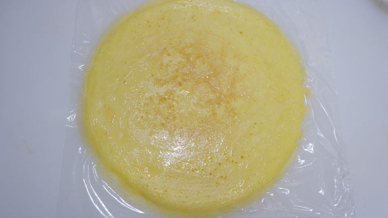 赤豆糯米蛋卷,案板上铺一张保鲜膜，将煎好的蛋饼放在上面。
