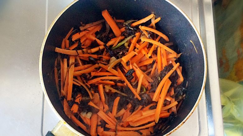 梅干菜炒意面,加入胡萝卜丝，翻炒至胡萝卜丝八成熟。