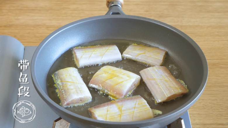 红烧带鱼12m+,热锅倒油，七八分热的时候，放入带鱼段，煎熟定型~