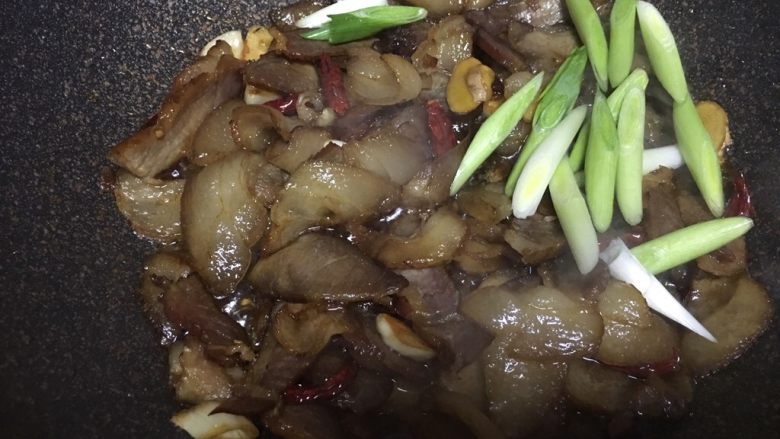 腊肉干锅,最后下大蒜苗的根部部分，稍翻炒下大蒜苗蒜部分，翻炒断生转至砂锅中