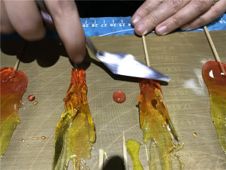 烈火雄心-水晶糖艺火焰棒糖,用尖头刮刀将尾端进行修整，将竹签子包裹紧实。