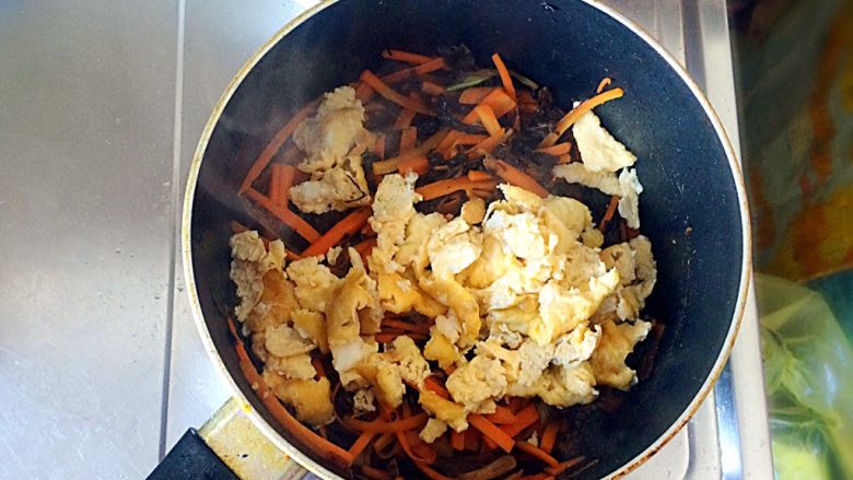 梅干菜炒意面,胡萝卜丝八成熟时，倒入鸡蛋，翻炒均匀。