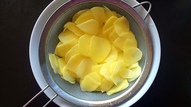 黑胡椒土豆玫瑰卷,将用淡盐水洗过的土豆片放入筛子，沥干水分。
