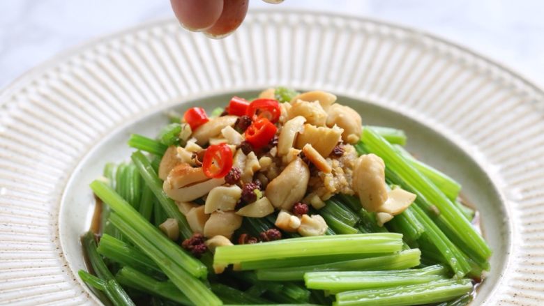 腰果仁炝芹菜,将腰果仁碎、花椒粒、小米辣丁撒在芹菜上。