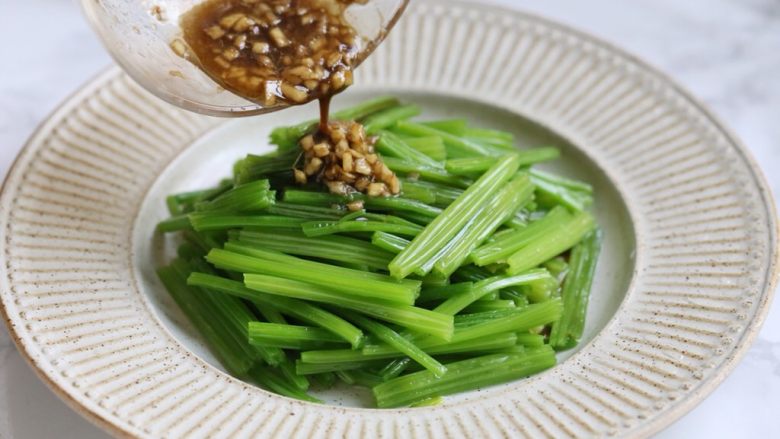 腰果仁炝芹菜,将味汁淋入装盘的芹菜中拌匀。