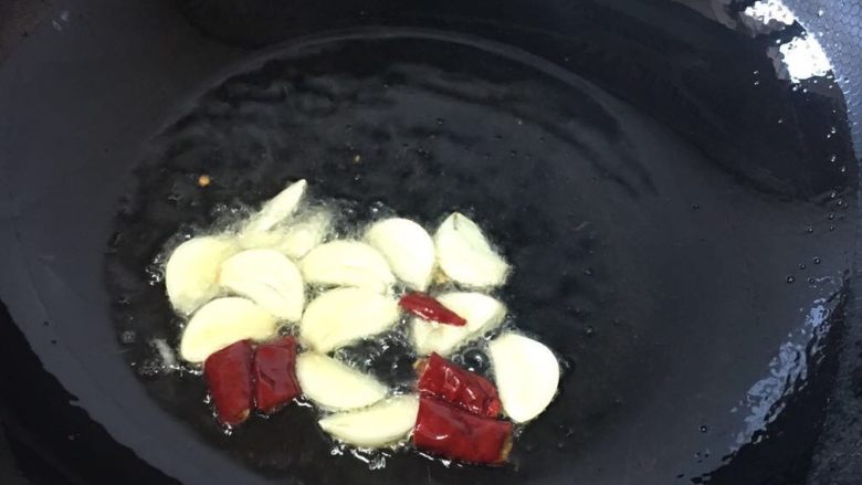 培根手撕包菜,锅里放油烧热爆香蒜片和辣椒