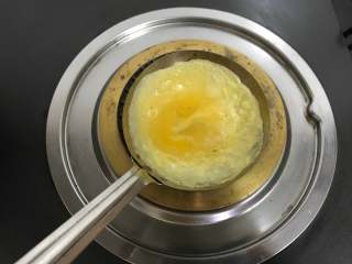 鲜肉蛋饺,倒入一勺蛋液，轻轻地旋转，使蛋液均匀地铺满勺子。