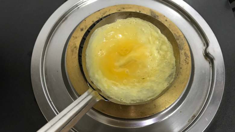 鲜肉蛋饺,倒入一勺蛋液，轻轻地旋转，使蛋液均匀地铺满勺子。