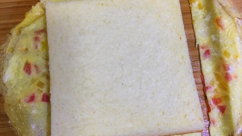 宝宝辅食12M➕：蔬菜奶酪三明治,把鸡蛋饼放在吐司上，根据吐司形状切成方形鸡蛋饼