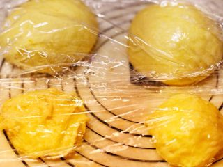 南瓜麻薯红豆面包,将面团分割两块，排气滚圆，麻薯面团也分两部分，盖保鲜膜松弛20分钟。