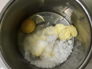 荷花椰蓉酥,把软化好的黄油和鸡蛋白砂糖一起放入容器里，用电动打蛋器打至砂糖融化