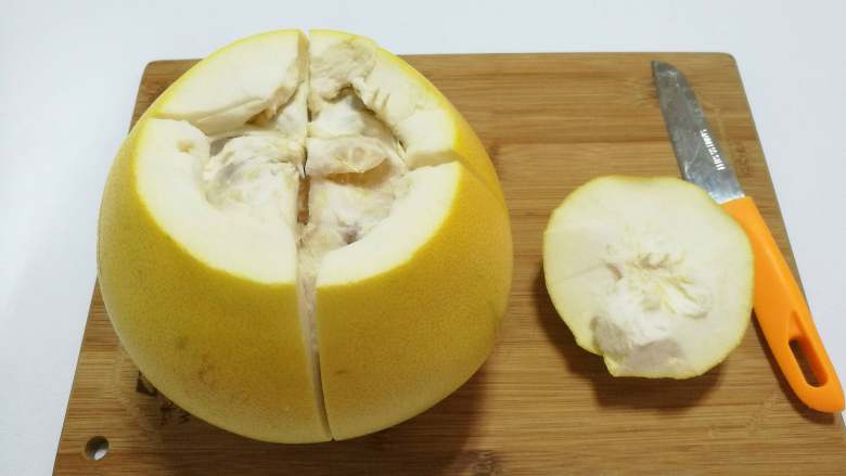 糖渍柚皮丝,削掉柚子顶尖部位，用刀将柚子划十字形，从上往下划开。