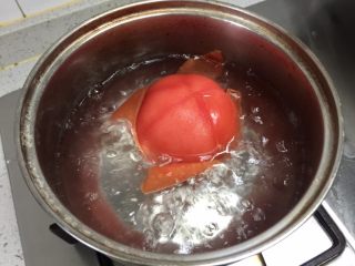 番茄芝心鸡蛋卷饼,锅里放是凉水烧开，把番茄表面烫一下，去掉表皮。