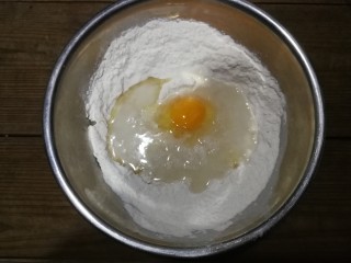 自制安心油条,将泡打粉和盐放入面粉里，用筷子搅匀后加入鸡蛋、水和玉米油