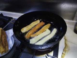 自制安心油条,大锅加入适量玉米油，大火将油温烧至筷子戳进去起大泡，然后将做好的油条生坯放入油锅炸制，两面金黄捞出即可